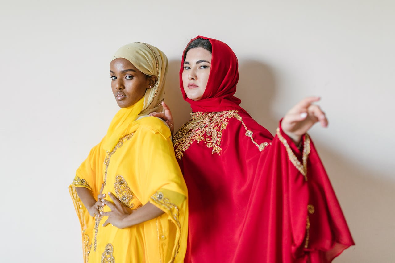 who-we-are Two women in vibrant yellow and red hijabs showcasing elegant Muslim fashion and modest clothing.