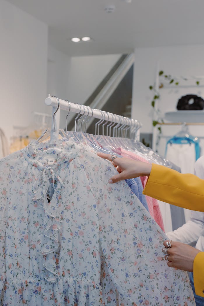 services-02 Woman browsing floral print dresses on a clothing rack indoors in a fashion store.